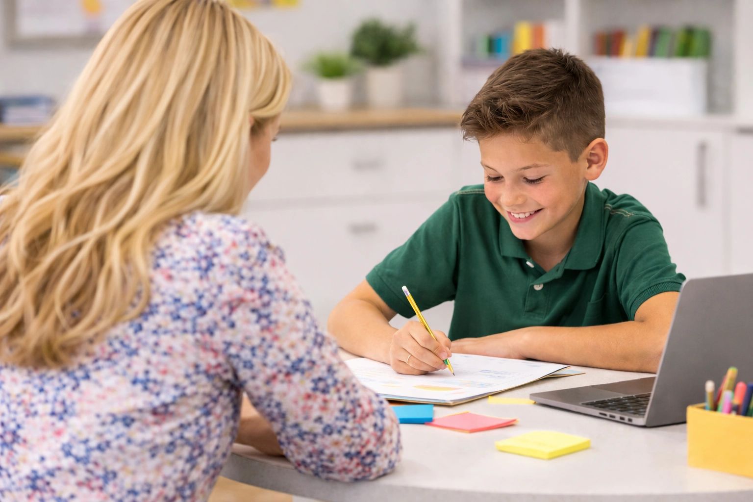 Young student studying at desk with teacher